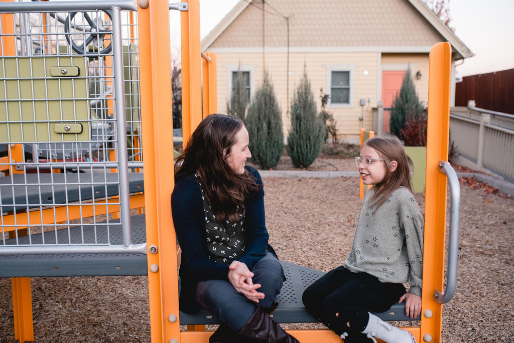 Therapist talks with a child on a playground.